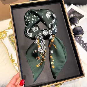 Detail of silk scarf with white roses and golden chain patterns on green fabric