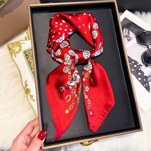 Detail of red silk scarf with white dots, rose prints and gold chain patterns on a tray