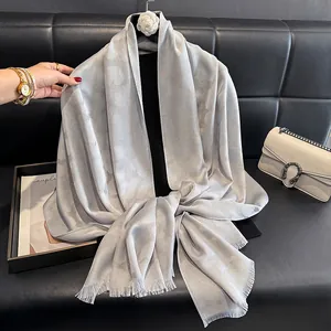 Detalle de bufanda jacquard gris plateado con sutil efecto purpurina y bordes de flecos