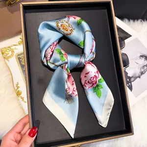 Detailed view of elegant light blue silk scarf with pink floral and golden chain patterns