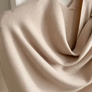 Close-up of beige knitted shawl featuring fine ribbed texture and soft fabric drape