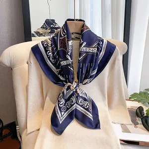 Close-up of luxury dark blue geometric pattern silk scarf tied on a beige sweater neck