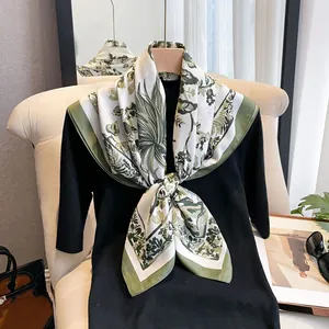 Detail of silk-like scarf featuring tropical green palm leaf print and contrast border