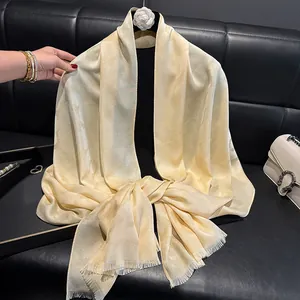 Detalle de una bufanda de seda color champán con textura jacquard y bordes deshilachados