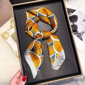 Close-up of orange silk scarf with Art Deco fan patterns in a minimalist gift box