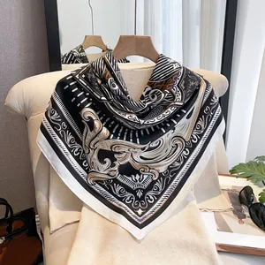 Detailed view of luxury silk scarf with baroque gold patterns on a white sofa