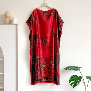 Detail of red satin kaftan dress featuring traditional plum blossom print and ethnic border