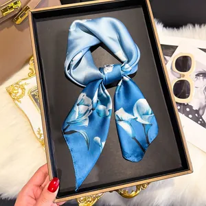 Detail of blue floral silk twilly scarf with lily pattern on a black display tray