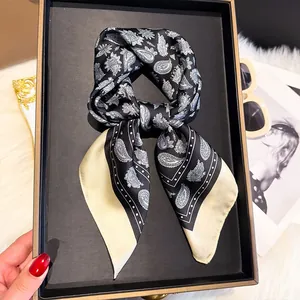 Detail of a paisley printed square scarf tied in a bow on a luxury display tray