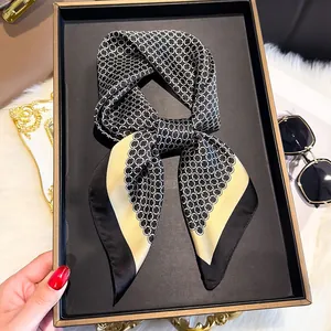 Detail of silk scarf tied in a bow featuring black and white chain patterns with yellow edges