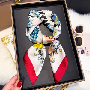 Artistic printed silk scarf with red border displayed in an elegant gift box setup