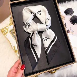 Detail of a chic black and white silk scarf tied in a bow on a luxury tray with accessories