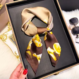 Detail of silk scarf with yellow calla lily print and two-tone satin texture in a tray
