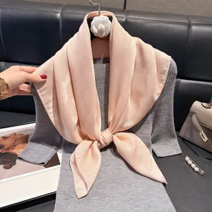 Elegante sciarpa di seta rosa chiaro su un abito in maglia grigio con spilla di perle