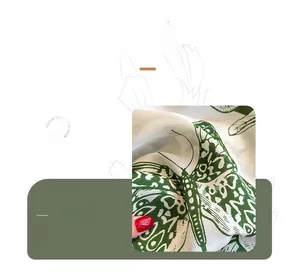 Gros plan sur tissu soyeux avec imprimé papillon vert et texture lisse brillante