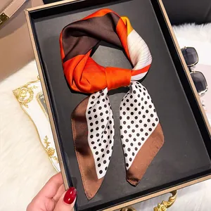 Detail of satin silk scarf with orange color blocks and black polka dots in a gift box