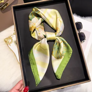 Detail view of a floral silk scarf tied in a bow inside a premium black gift box