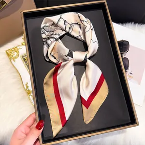 Close-up of silk square scarf with floral patterns on a black tray with accessories