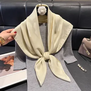 Dettaglio di un foulaggio in seta champagne con jacquard su un maglione grigio a maglia