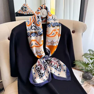 Détails d'un foulard en soie de luxe aux motifs paisley et floraux orange et bleu