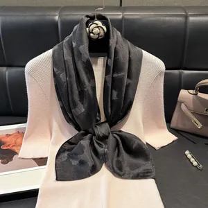 Dettaglio foulard in seta nera con motivo a stelle e glitter su maglia rosa pastello