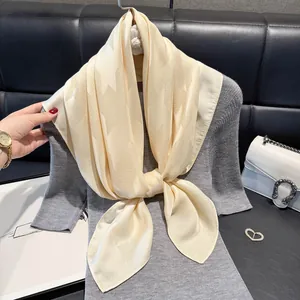 Close-up of champagne silk scarf with star jacquard pattern on grey knit dress