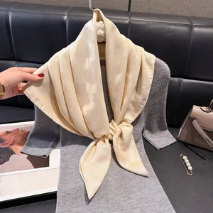 Elegante sciarpa di raso beige annodata a fiocco sulla scollatura di un abito in maglia
