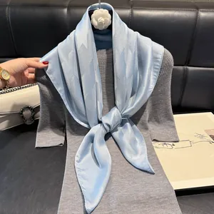 Close-up of light blue silk scarf with jacquard pattern tied on a knit top