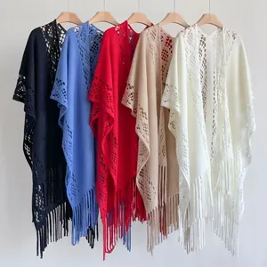 Détail de châles en maille ajourée avec de longues franges en cinq couleurs sur cintres
