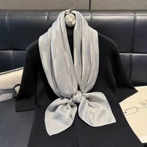 Elegant silver-grey geometric houndstooth scarf tied in a bow on a black sweater