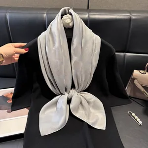 Dettaglio di un foulard quadrato grigio chiaro con trama jacquard e drappeggio elegante