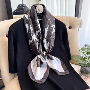 Détail d'un foulard élégant en soie avec motifs floraux sur un haut noir chic