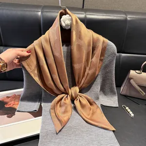 Dettaglio di elegante foulard in raso color caffè con trama jacquard su abito grigio