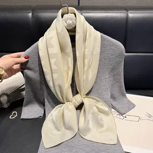 Detail of elegant beige silk scarf with geometric jacquard pattern on a stylish outfit