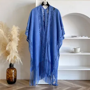 Châle en maille ajourée bleu vif avec franges sur un présentoir élégant