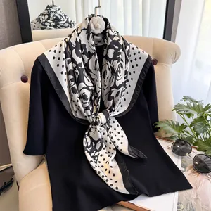 Détail d'un foulard effet soie avec motif rose noir et blanc et clip fleur de camélia