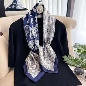 Nahaufnahme des Seidenschals mit Paisley-Muster in Blau-Weiß auf schwarzem Strick