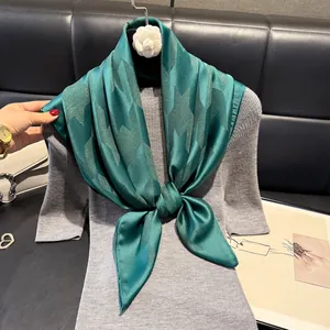 Detail of emerald green satin scarf with star pattern on grey knit sweater