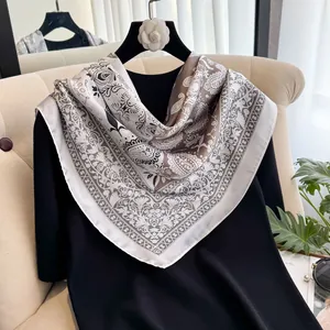 Detailaufnahme eines seidigen quadratischen Seidentuchs mit Paisley-Muster am Kleiderbügel