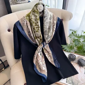 Detail eines Seidenschals mit Paisleymuster über einem schwarzen Pullover auf dem Sofa