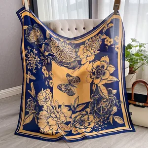 Detailansicht eines Seidenschals mit goldenem Blumenmuster und Schmetterling auf Marineblau