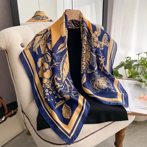 Nahaufnahme von Seidenschal mit blau-gelbem Blumendruck auf einem weißen Stuhl
