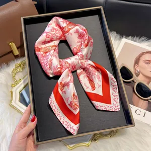Elegant red floral square silk scarf with bird pattern on a stylish accessory tray