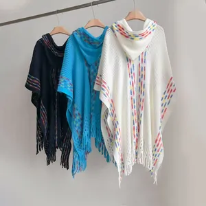 Details von bunten Strick-Ponchos mit Fransen und Kapuzen auf Holzkleiderbügeln