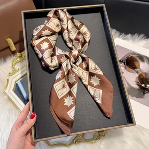 Detail of silk satin scarf with palm tree and star print in warm brown and cream tones