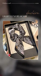 Detail of elegant paisley print silk scarf in black and brown on a minimalist tray