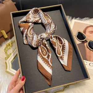 Close-up of brown paisley print silk scarf displayed on tray with fashion accessories