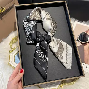 Close-up of silky paisley scarf showing fine stitching and elegant drape on a tray