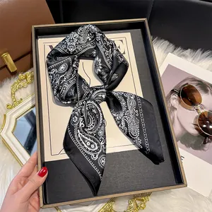 Classic paisley silk scarf in black and white tied elegantly next to a fashion magazine