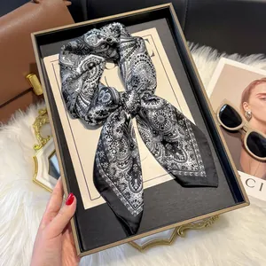 Detail of elegant black and white paisley silk scarf tied in a bow on a display tray